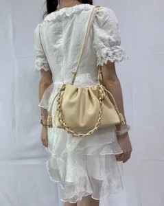 Gros plan sur un sac nuage plissé en cuir beige avec bandoulière chaîne pour femmes.