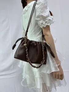 Sac nuage plissé en cuir souple marron foncé avec bandoulière chaîne et cordon. Vue détaillée du style.