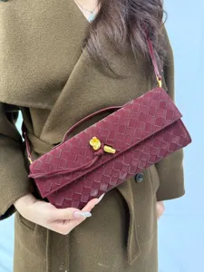 Burgundy woven leather baguette shoulder bag detail with an iconic gold knot latch.