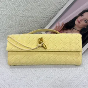 Yellow woven leather clutch bag with metal knot closure, elegant long evening bag detail.