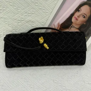 Black woven evening clutch bag with gold knot hardware detail, elegant vintage baguette style.