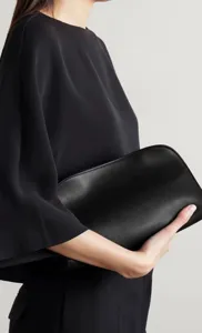 Λεπτομερής λήψη μινιμαλιστικού μαύρου δερμάτινου τσαντάκι, λεία επιφάνεια δέρματος, κομψό.