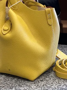 Yellow genuine leather bucket bag, classic basket handbag with top handles and pebbled texture.
