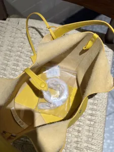 Yellow leather bucket bag interior detail showing suede lining and inner accessories.