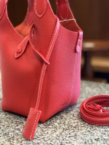 Detailed view of the red genuine leather bucket bag with contrasting stitching and texture.