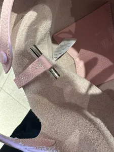 Pink leather bucket bag interior detail, featuring metal hardware closure and inner pocket.