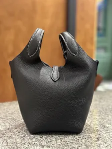 Close-up view of premium black genuine leather bucket bag showing fine litchi grain texture.