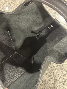 Detailed interior view of black genuine leather bucket bag with contrast stitching.