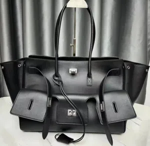 Detailed shot of black leather multi-pocket tote bag, showcasing metal hardware and wings.