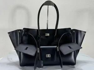 Black leather winged tote bag with front pockets for commuting and daily use.