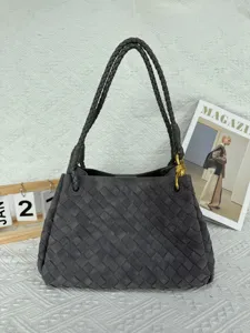 Detailed view of the dark grey faux suede woven shoulder bag with chic metal knot hardware.