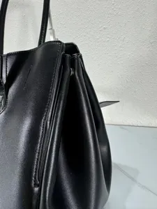 Black leather handbag side detail close up showcasing premium texture and stitching craftsmanship.