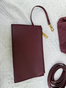 Burgundy leather pouch clutch bag with detachable strap and classic woven design detail.