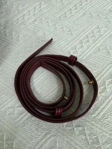 Detailed view of a rich burgundy leather bag replacement strap with gold tone hardware accents.