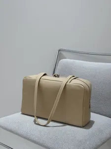 Minimalist beige lambskin bowling bag with dual top handles and secure zip closure for women.