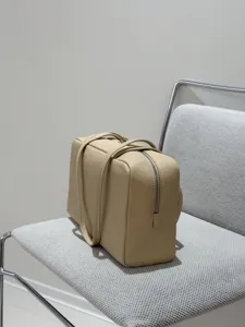 Minimalist leather bowling bag for women, elegant beige boston handbag with dual handles.