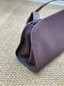 Λεπτομέρεια τσάντας clutch από σκούρο καφέ δέρμα με λεπτές ραφές και πολυτελή υφή.