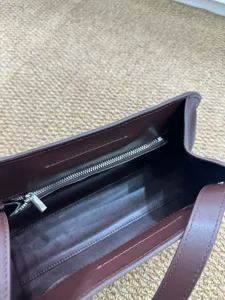 Εσωτερική λεπτομέρεια δερμάτινης τσάντας clutch σε σκούρο καφέ με τσέπη φερμουάρ.