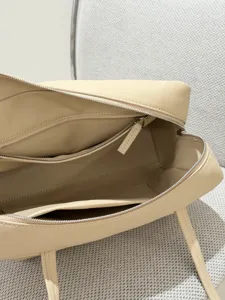 Beige lambskin bowling bag detail, luxury minimalist boston bag with zip pocket and dual top handles.
