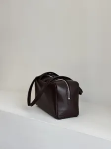 Dark brown leather bowling bag Boston bag with dual top handles and zip closure detail.