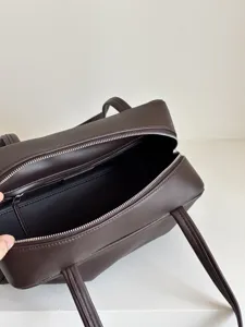 Dark brown leather bowling bag detail, zipper closure and dual top handles for daily use.