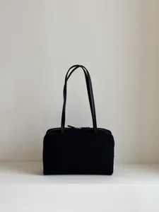 Detailed view of the black leather bowling bag featuring structured design and dual handles.