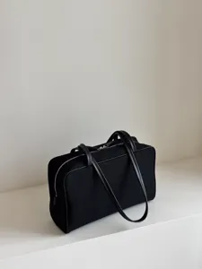 Minimalist black canvas boston bag with leather trim and dual handles, detailed view.