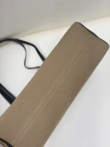 Close-up detail of cylindrical canvas shoulder bag with fine stitching and black leather trim.