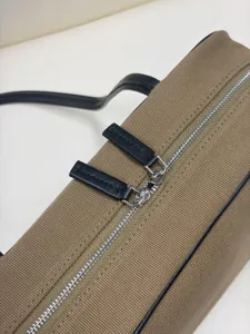Detail view of khaki canvas boston bag with black leather trim and silver zipper hardware.