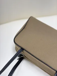 Close-up view of premium canvas bag with black leather piping and refined zipper hardware.