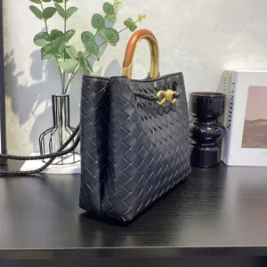Detailed view of black woven leather tote bag featuring unique metal wood handle design.
