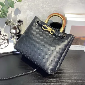 Black woven leather handbag with metal knot handle, stylish shoulder tote bag detail shot.