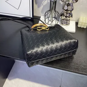 Black woven leather handbag with metal knot handle, luxury design tote bag for women commuting.