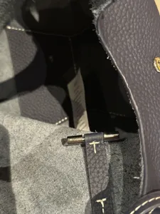 Detailed close-up of pebbled leather handbag interior with metal hardware and fine stitching.