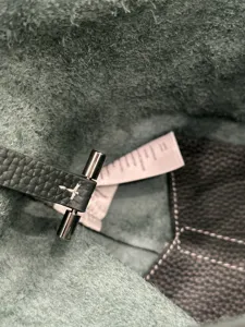 Detailed close-up of premium leather bucket bag interior, featuring metal toggle and stitching.