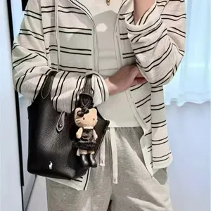 Black leather bucket handbag with pony logo and cute doll pendant, classic old money style.