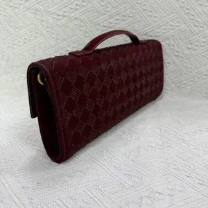 Detailed view of the burgundy woven leather clutch bag showing intricate craftsmanship and texture.