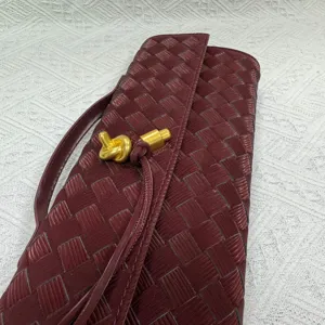 Burgundy woven leather clutch bag detail, elegant vintage evening bag with chic gold latch.