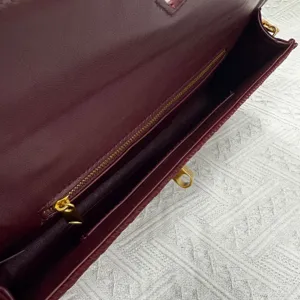 Burgundy leather evening clutch bag interior detail featuring gold hardware and ring closure.