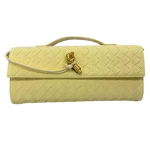 Yellow woven leather clutch bag featuring metal knot closure and elegant baguette shape style.