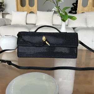 Sac de soirée noir en strass avec fermoir serpent doré, poignée métallique et bandoulière chic.