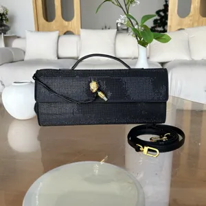 Vue détaillée de la pochette de soirée noire en strass avec poignée et fermoir doré.