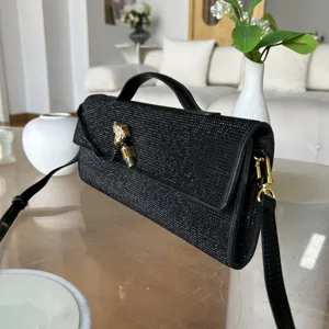 Vue détaillée du sac de soirée noir en strass avec poignée en métal et bandoulière dorée.