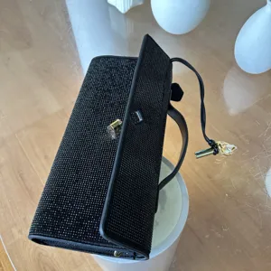 Détail de pochette de soirée noire en strass, texture cristal étincelante et fermoir en métal.