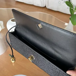 Élégante pochette de soirée noire en strass avec fermoir métallique et bandoulière.