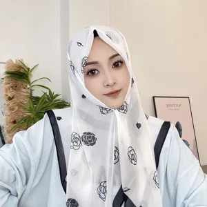 Detalle de hiyab de gasa con elegante estampado floral de rosas negras en tela blanca.