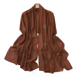 Close-up detail of brown chiffon scarf featuring sparkling rhinestone polka dots design.