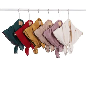 Close-up view of multiple solid color wrinkled square scarves hanging neatly on wooden hangers.