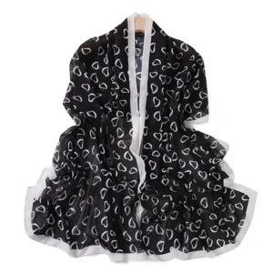 Vista dettagliata della sciarpa lunga in chiffon con stampa cuori bianco e nero, texture elegante.