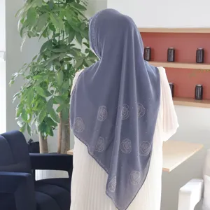 Detailansicht des grauen Chiffon Hijabs mit funkelnden Strassrosenmustern und feinen Falten.